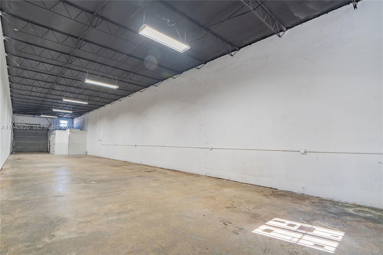 An empty industrial warehouse space features a concrete floor, white walls, and exposed ceiling rafters — 1672 W 31st Pl, Hialeah FL 33012, HIALEAH, FL