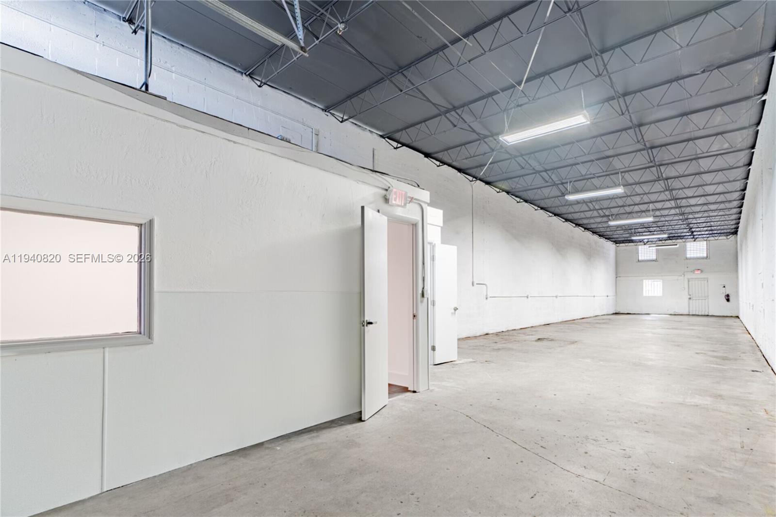 An empty industrial warehouse space features white walls, a concrete floor, and exposed ceiling trusses — 1672 W 31st Pl, Hialeah FL 33012, HIALEAH, FL
