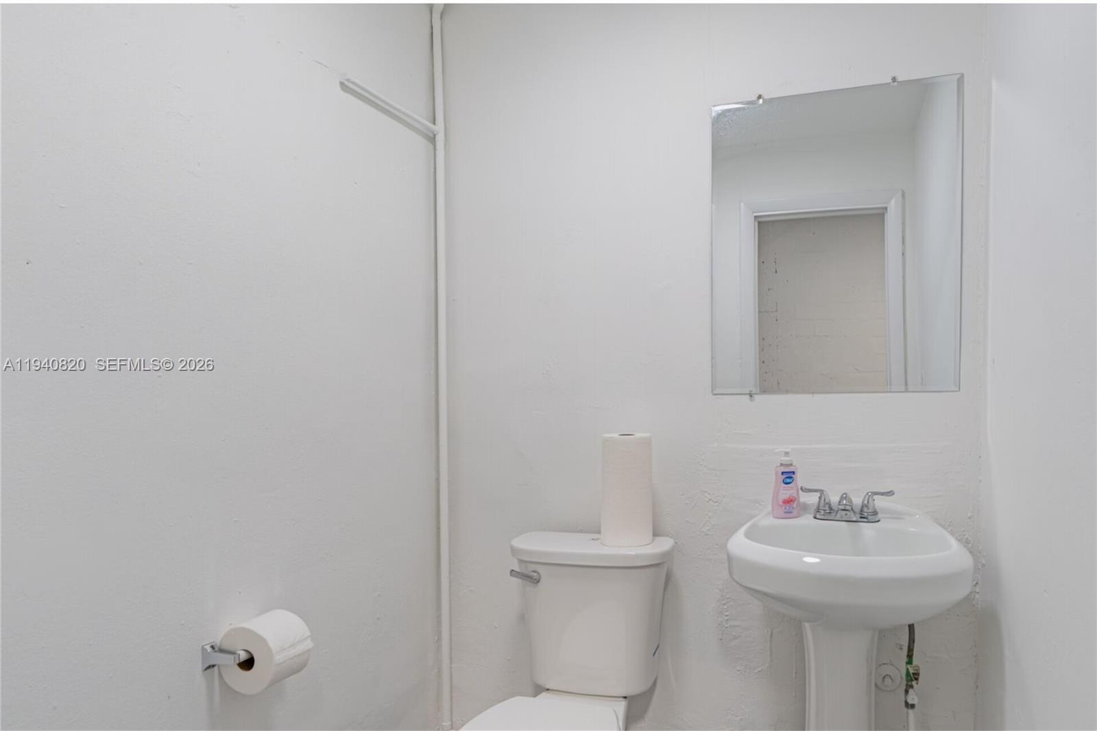 A small bathroom features a white pedestal sink, a toilet, and a wall-mounted mirror — 1672 W 31st Pl, Hialeah FL 33012, HIALEAH, FL