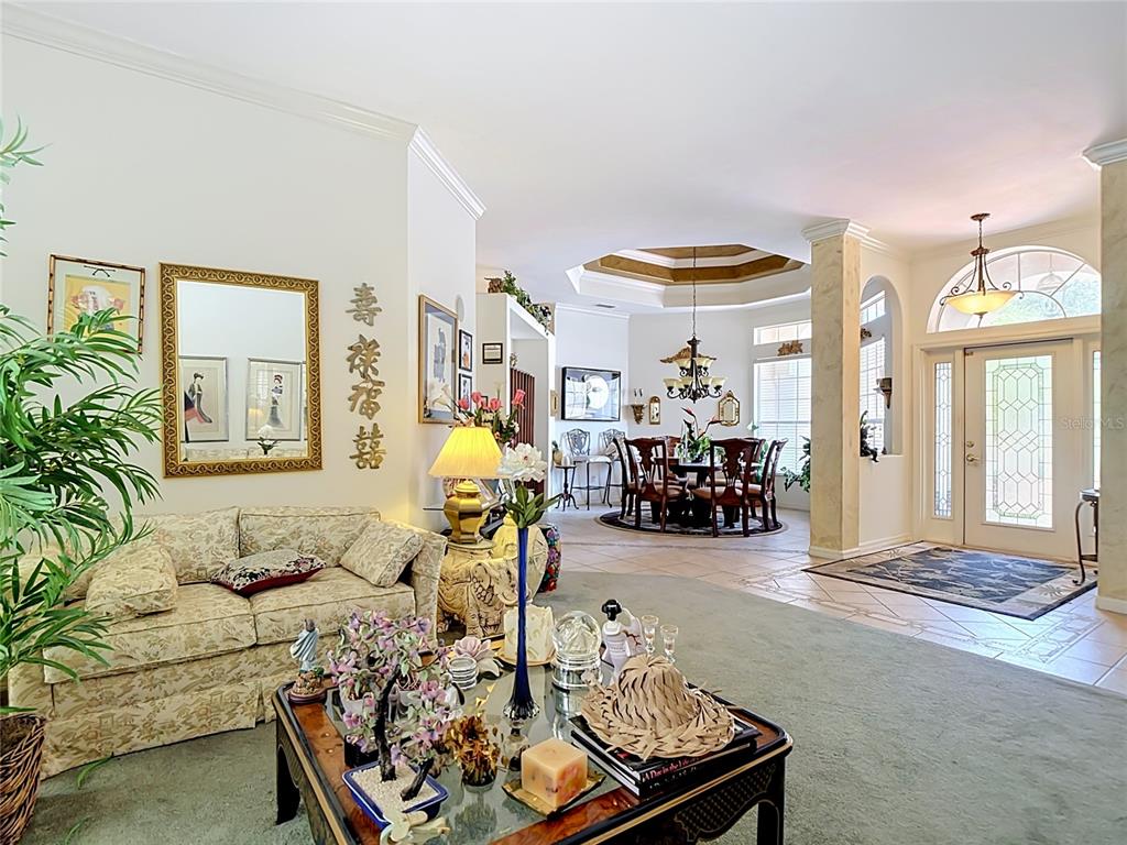 A living room with a floral sofa, coffee table, and an adjacent dining area — 2221 OXFORD RIDGE CIRCLE, LEHIGH ACRES, FL