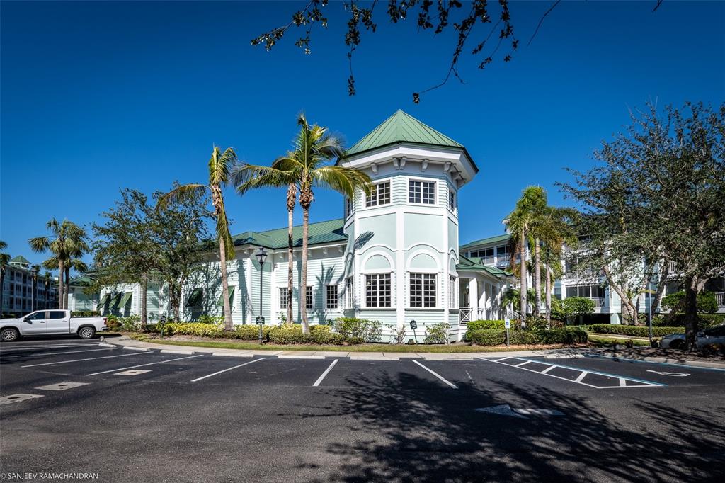 A light green building with a tower and metal roof stands beside a parking lot — 5125 MELBOURNE STREET UNIT E201, PUNTA GORDA, FL