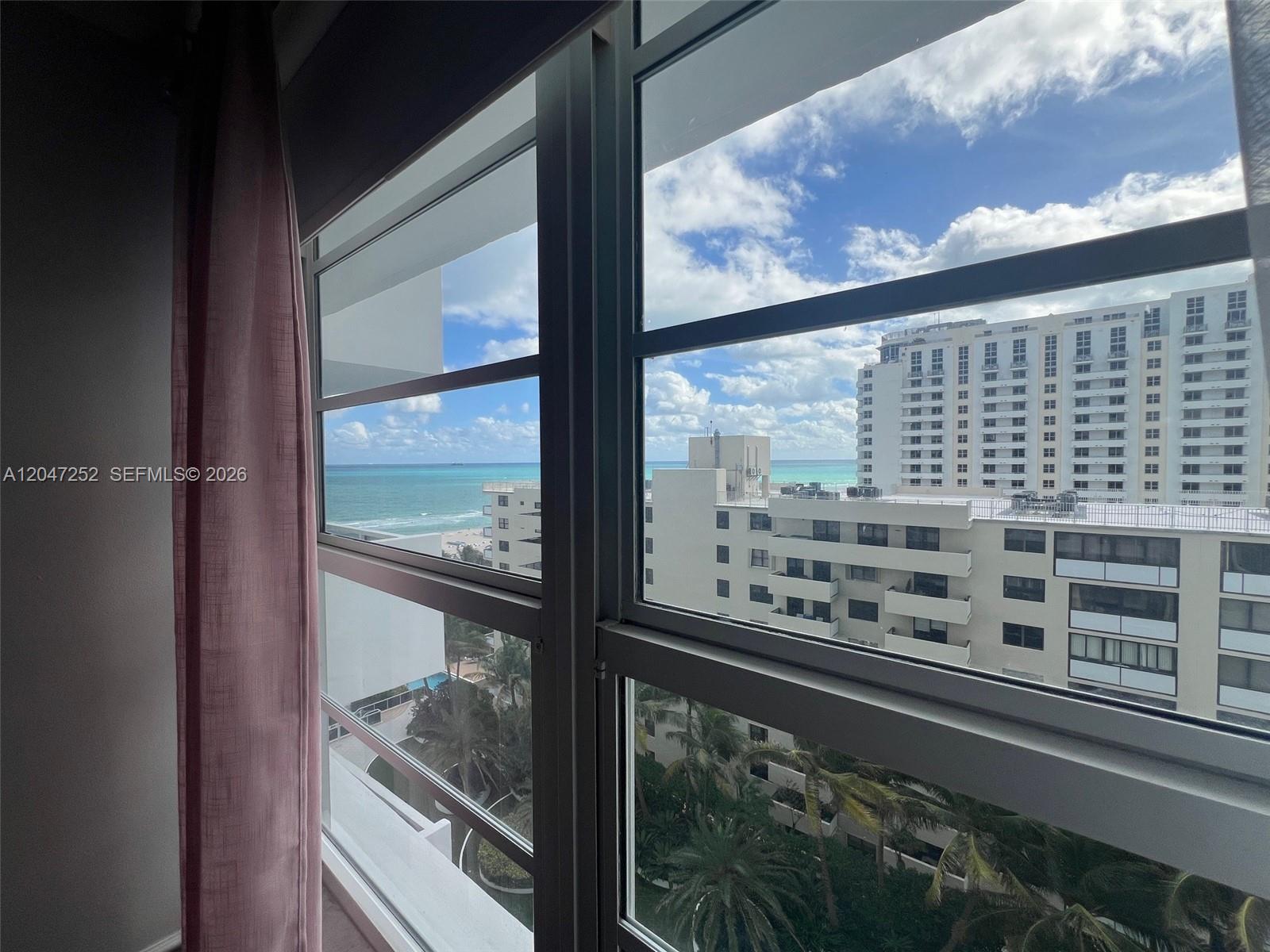 A view of the ocean and nearby buildings through a large window with pink curtains — 100 Lincoln Rd # 1126, Miami Beach FL 33139, MIAMI BEACH, FL