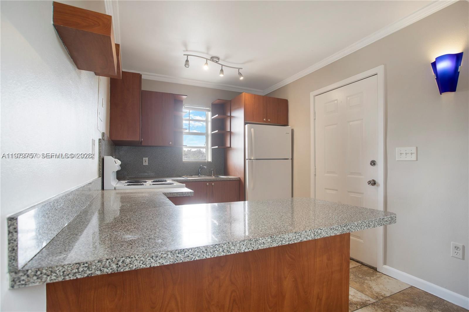 A kitchen features wood cabinets, granite countertops, a white refrigerator, and a track light fixture — 1020 SW 7th St # 9, Miami FL 33130, MIAMI, FL