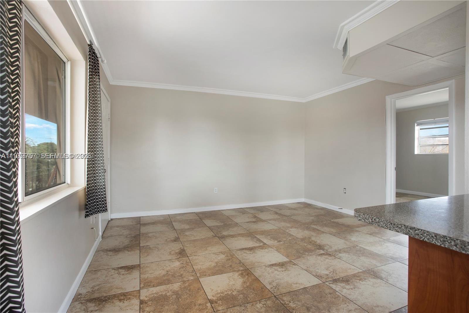 An empty room features beige walls, large square floor tiles, and a window with curtains — 1020 SW 7th St # 9, Miami FL 33130, MIAMI, FL