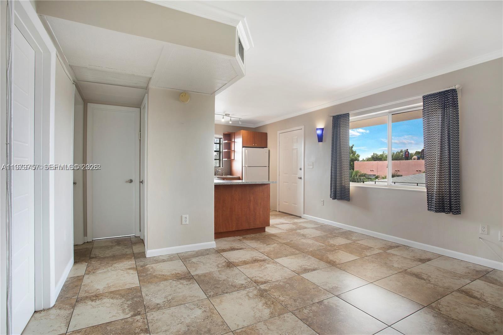 This room features tiled floors, a kitchen area with wooden cabinets, and a large window — 1020 SW 7th St # 9, Miami FL 33130, MIAMI, FL