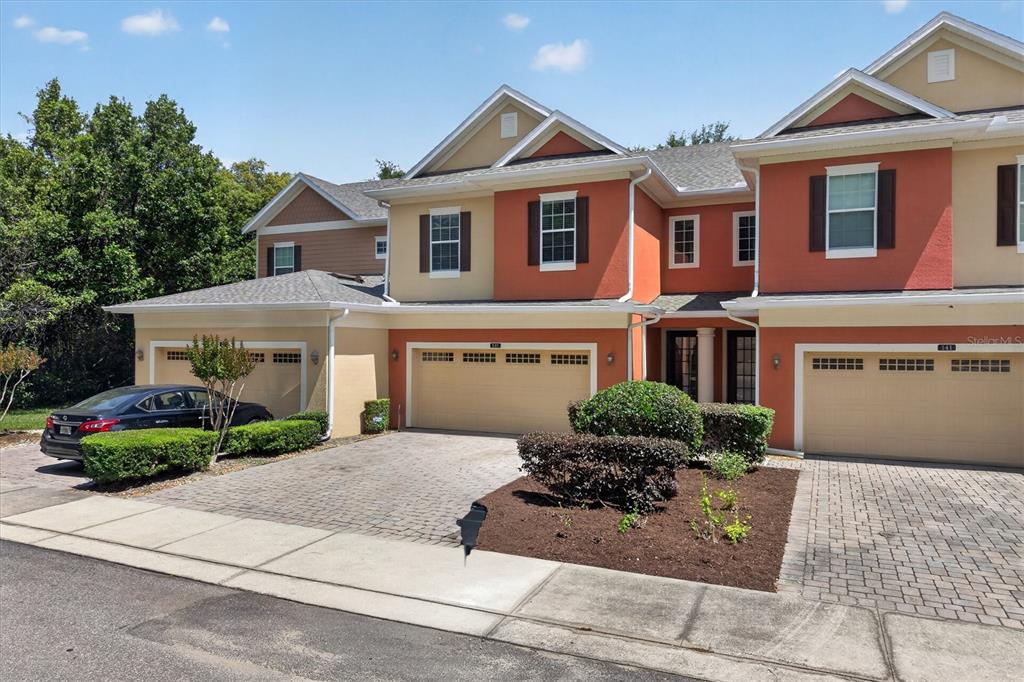 A multi-story townhouse complex features orange and tan stucco exteriors with attached garages — 145 STENHOUSE LANE, LONGWOOD, FL