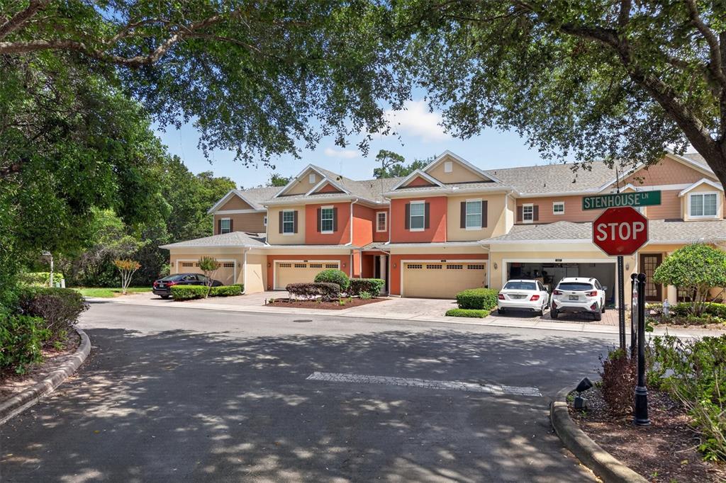 A multi-unit townhouse building with attached garages and a stop sign in the foreground — 145 STENHOUSE LANE, LONGWOOD, FL