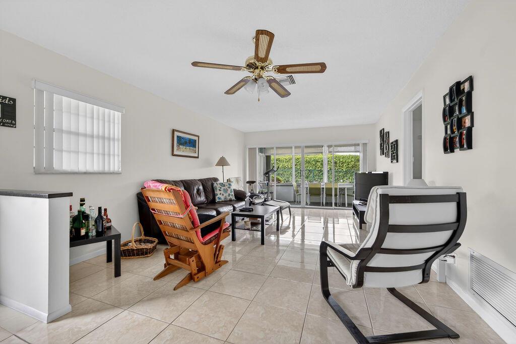 A living room features tile flooring, a ceiling fan, a sofa, and sliding glass doors — 622 Hummingbird Lane, Delray Beach FL 33445, DELRAY BEACH, FL