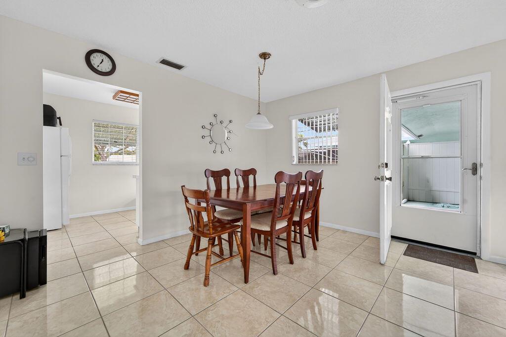 A dining area with tile floors, a wooden table with chairs, and an exterior door — 622 Hummingbird Lane, Delray Beach FL 33445, DELRAY BEACH, FL