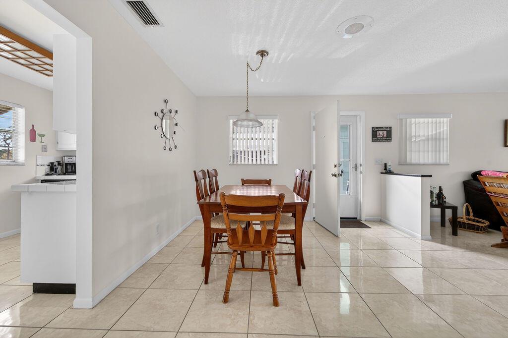 A dining area features a wooden table and chairs, tile flooring, and a wall clock — 622 Hummingbird Lane, Delray Beach FL 33445, DELRAY BEACH, FL