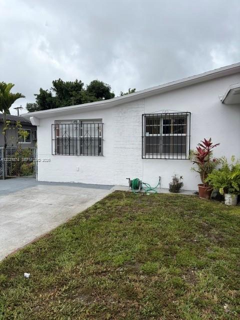 The exterior of a white house features two windows with black security bars and grass — 336 E 41st St, Hialeah FL 33013, HIALEAH, FL