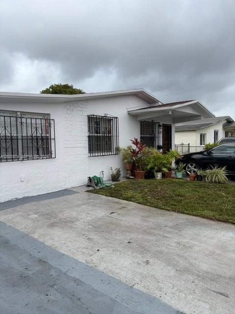 A white one-story house features a concrete driveway, metal window security bars, and potted plants — 336 E 41st St, Hialeah FL 33013, HIALEAH, FL