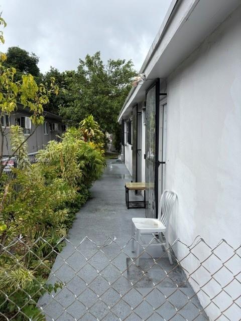 A narrow concrete walkway runs alongside a white building with a single chair — 336 E 41st St, Hialeah FL 33013, HIALEAH, FL