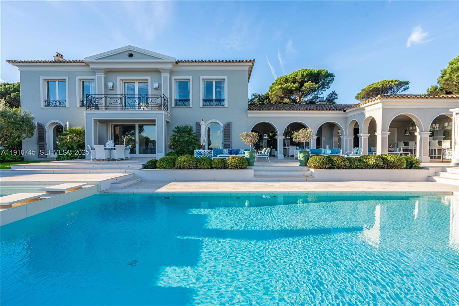 A two-story Mediterranean-style house features a large swimming pool and a covered arched patio — La quessine Le Paradis, FL, FL