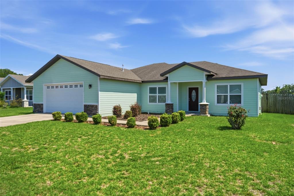 A light green single-story house with a two-car garage and a front porch — 23051 NW 4TH PLACE, NEWBERRY, FL