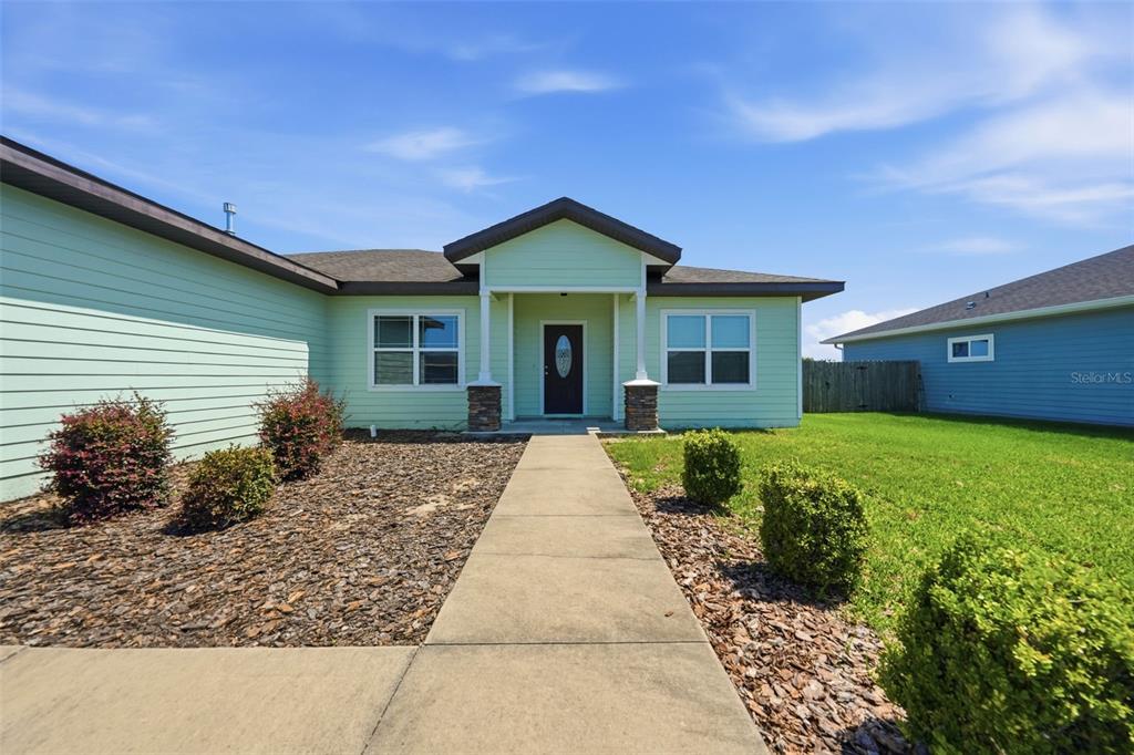 A light green house with a concrete walkway leading to the front entrance — 23051 NW 4TH PLACE, NEWBERRY, FL