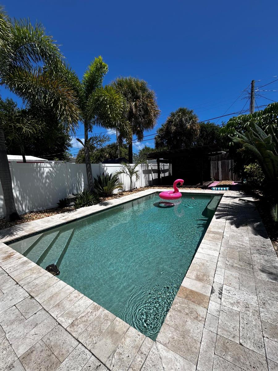 A rectangular swimming pool with a pink flamingo float sits in a landscaped backyard — 408 N J Street, FL 33460, FL