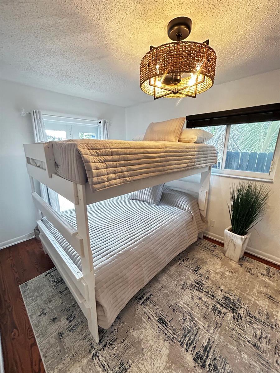 A bedroom features a white bunk bed, a woven drum light fixture, and a patterned rug — 408 N J Street, FL 33460, FL