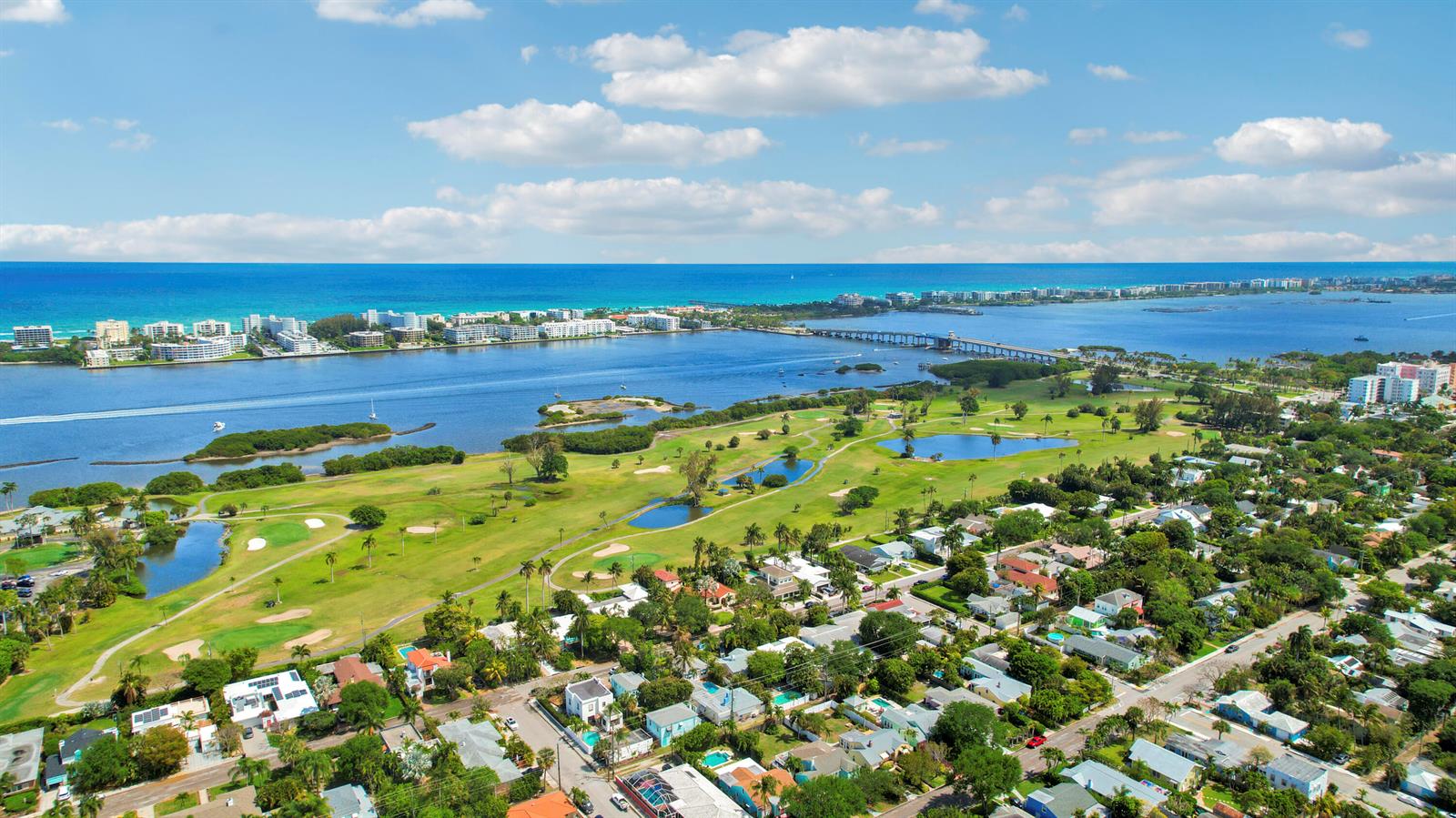 An aerial view shows a golf course, residential neighborhood, and a bridge over the water — 408 N J Street, FL 33460, FL