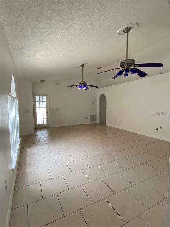 An empty room features light-colored tile flooring, white walls, and two ceiling fans — 6867 BELMAR DRIVE, ORLANDO, FL