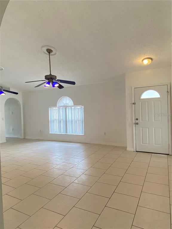 A living room with light tile flooring, a ceiling fan, and a white front door — 6867 BELMAR DRIVE, ORLANDO, FL