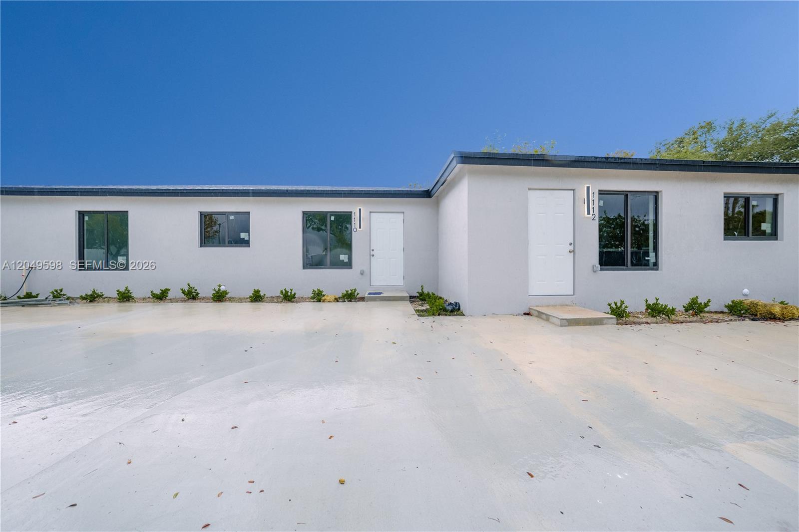 A single-story building with a white exterior, two front doors, and a concrete driveway — 1112 NW 81st St, Miami FL 33150, MIAMI, FL