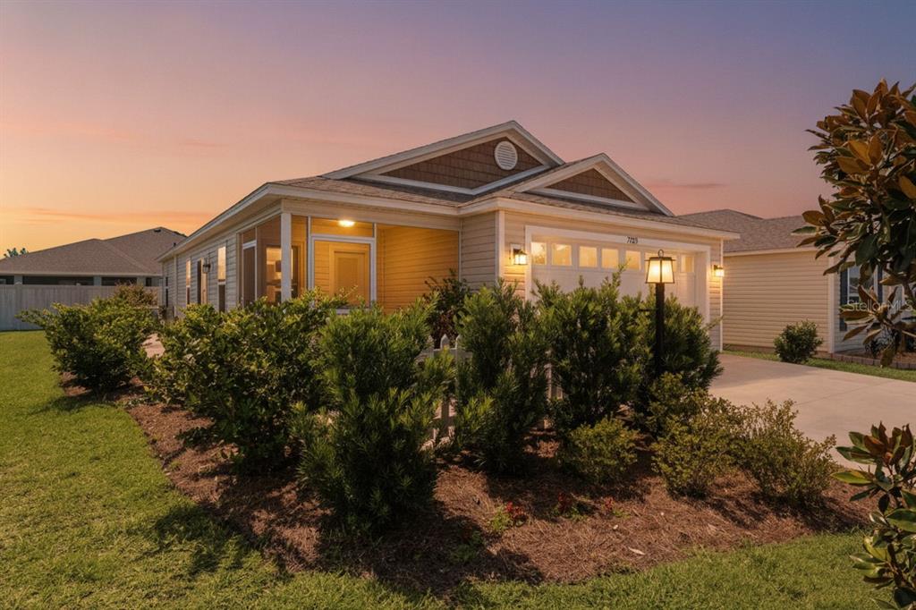 A single-story house with a screened porch, garage, and landscaped yard at sunset — 7185 FAY COURT, THE VILLAGES, FL