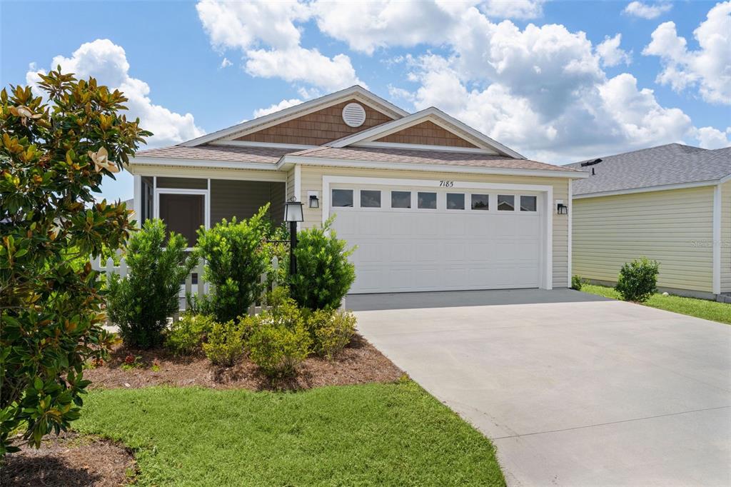 A single-story house with a two-car garage, light siding, and a front porch — 7185 FAY COURT, THE VILLAGES, FL