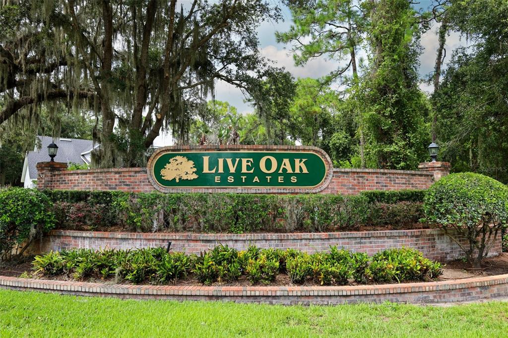 A brick entrance sign for Live Oak Estates sits in front of trees and landscaping — 11712 RAMBLING OAK BOULEVARD, ORLANDO, FL