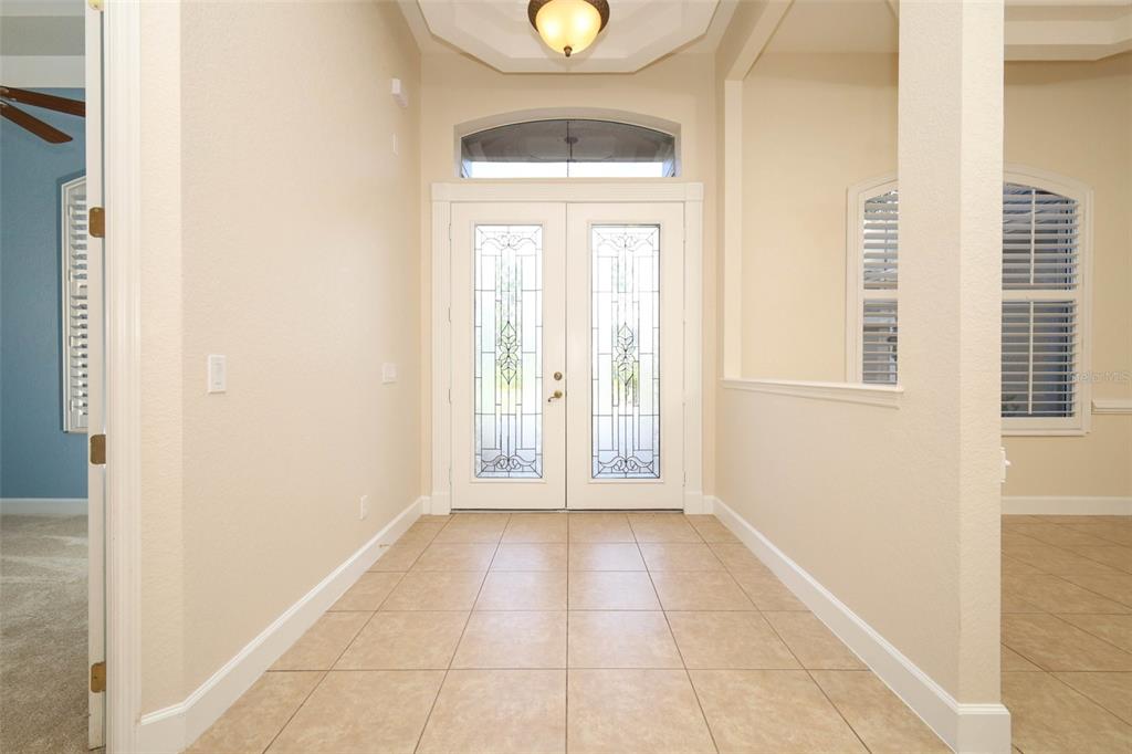 A tiled entryway features double glass-paneled front doors, a recessed ceiling, and a light fixture — 11712 RAMBLING OAK BOULEVARD, ORLANDO, FL