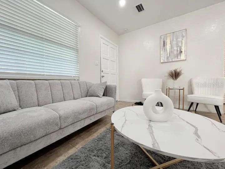 A living room features a grey sofa, a marble coffee table, and two white chairs — 3606 W BAY TO BAY BOULEVARD, TAMPA, FL