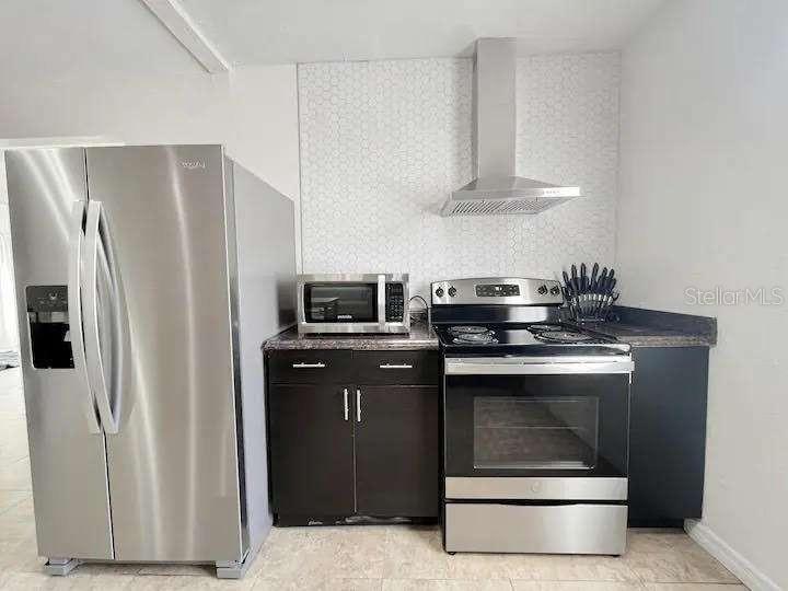 A kitchen features stainless steel appliances, dark cabinets, and a white patterned tile backsplash — 3606 W BAY TO BAY BOULEVARD, TAMPA, FL