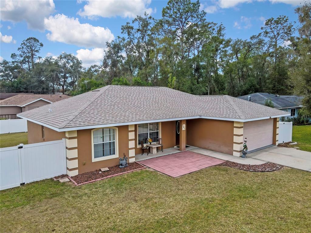 An aerial view of a single-story brown house with a tan roof and paved patio — 103 DAISY LANE, INVERNESS, FL
