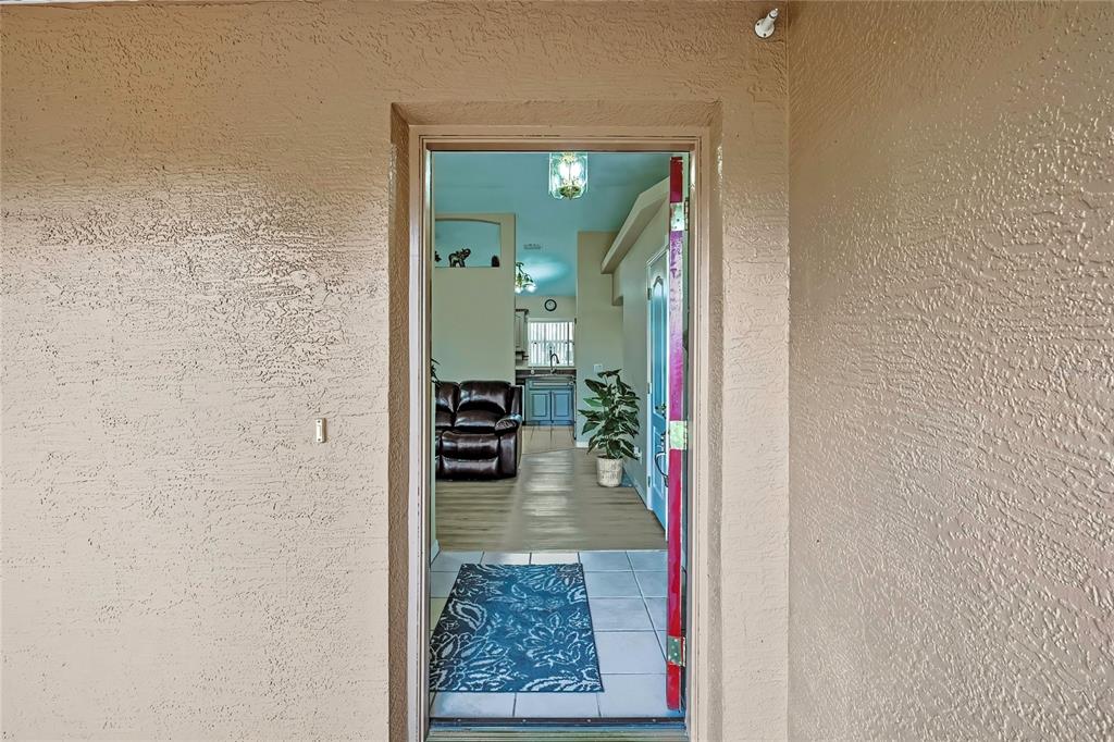 A view through an open doorway showing a tiled entryway, living area, and kitchen — 103 DAISY LANE, INVERNESS, FL