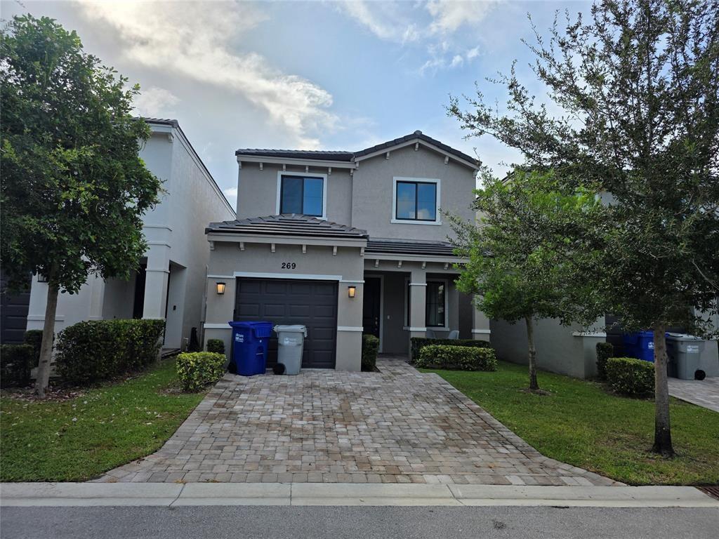 A two-story suburban house with a paved driveway, a single-car garage, and two trash bins — 269 NW 36th Avenue, Pompano Beach FL 33069, POMPANO BEACH, FL