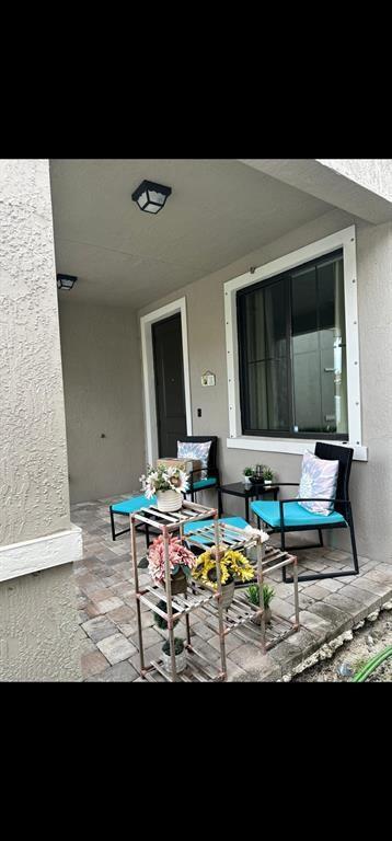 A covered patio features a paved floor, two chairs with blue cushions, and a tiered shelf — 269 NW 36th Avenue, Pompano Beach FL 33069, POMPANO BEACH, FL