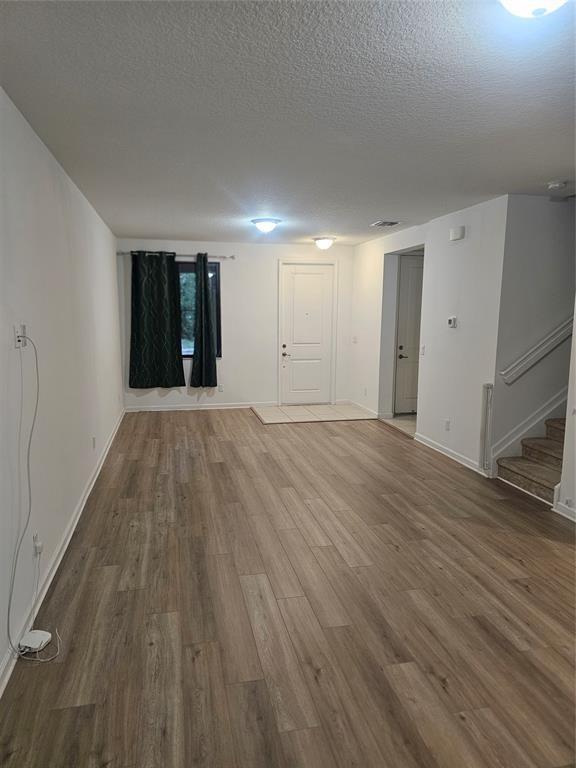 An empty living room features light wood-look flooring, white walls, and a staircase — 269 NW 36th Avenue, Pompano Beach FL 33069, POMPANO BEACH, FL