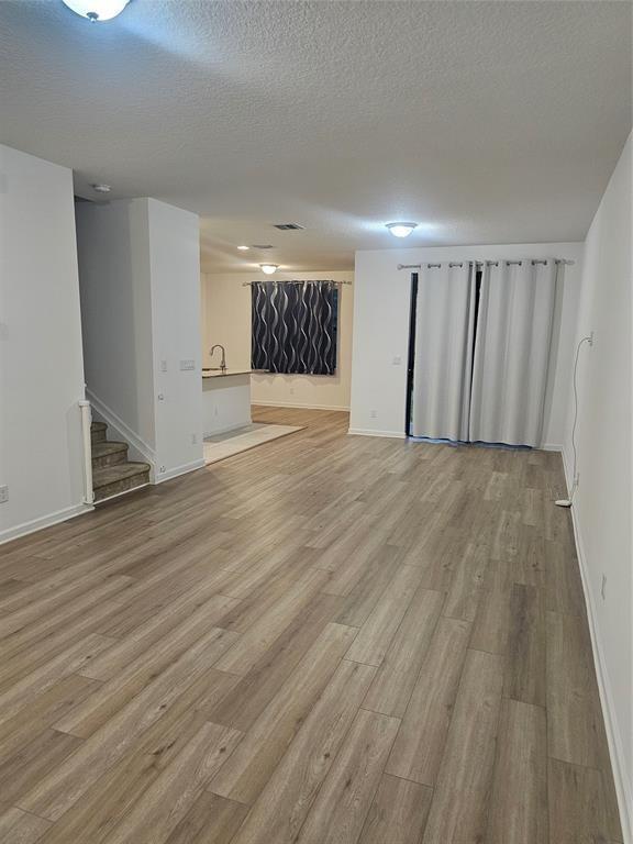 An open-concept living area features light wood-look flooring, a staircase, and a kitchen beyond — 269 NW 36th Avenue, Pompano Beach FL 33069, POMPANO BEACH, FL