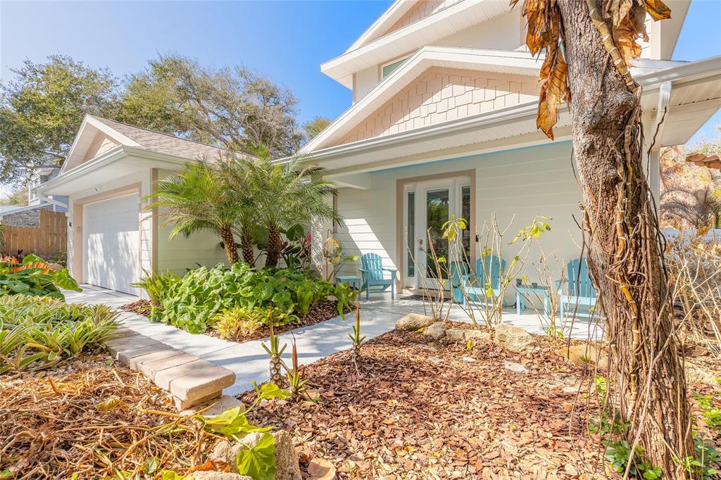 A light-colored house exterior features a front porch, a garage, and landscaped garden beds — 68 GLENVIEW AVENUE, PONCE INLET, FL