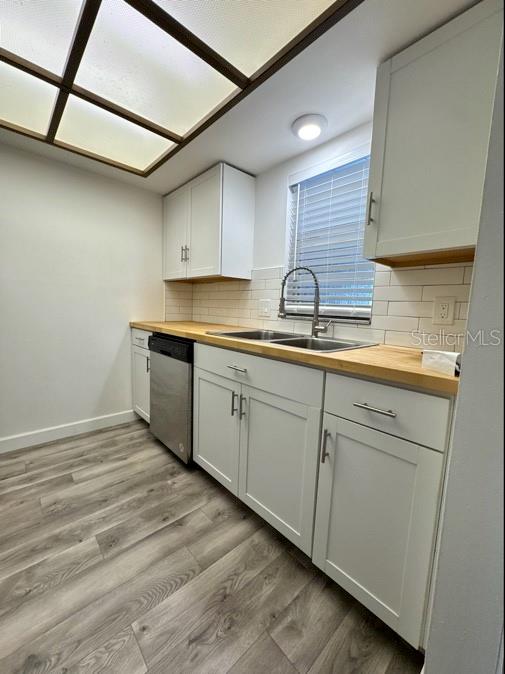 A kitchen features white cabinets, a wood countertop, a stainless steel dishwasher, and gray flooring — 9700 STARKEY ROAD UNIT 322, SEMINOLE, FL
