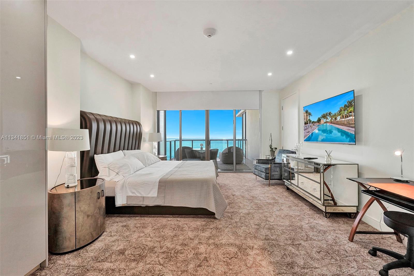 A bedroom features a large bed, mirrored furniture, a desk, and a balcony overlooking the ocean — 9703 Collins Ave # 2501, Bal Harbour FL 33154, BAL HARBOUR, FL
