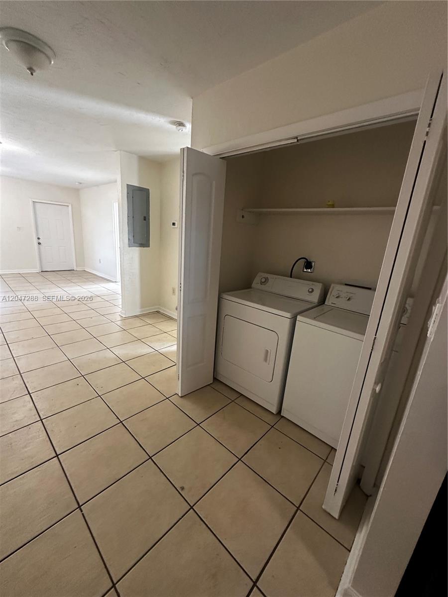 A laundry closet with a washer and dryer sits in a room with tiled floors — MIAMI, FL