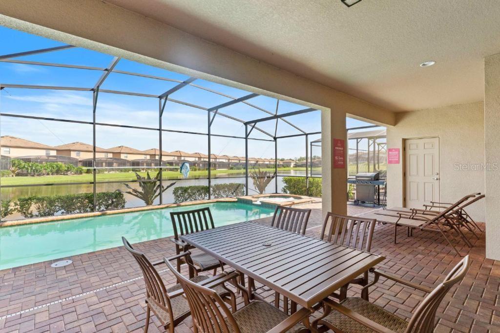 A covered patio features a dining set, lounge chairs, a pool, and a screened enclosure — 8815 MACAPA DRIVE, KISSIMMEE, FL