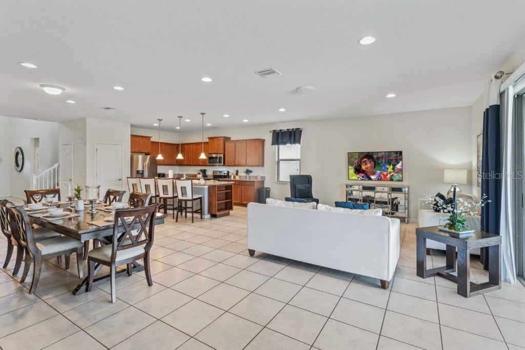 An open-concept living area features a dining space, kitchen with wood cabinets, and living room — 8815 MACAPA DRIVE, KISSIMMEE, FL