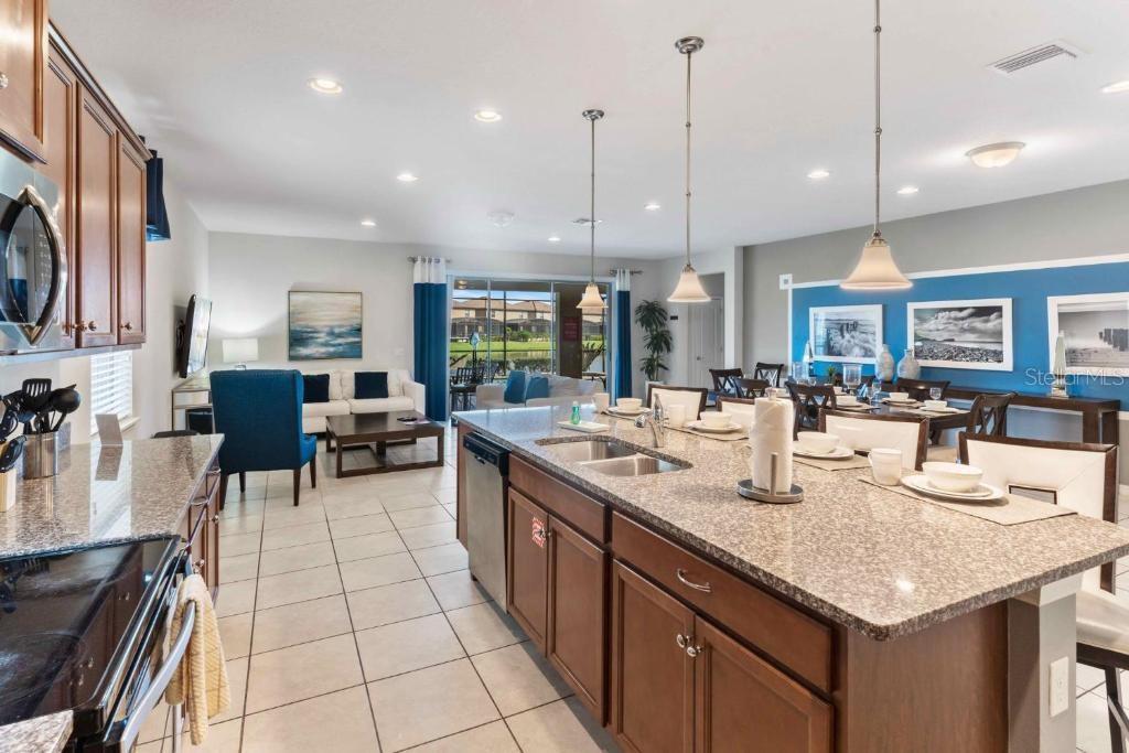 A kitchen island with granite countertops overlooks an open-concept living and dining area — 8815 MACAPA DRIVE, KISSIMMEE, FL