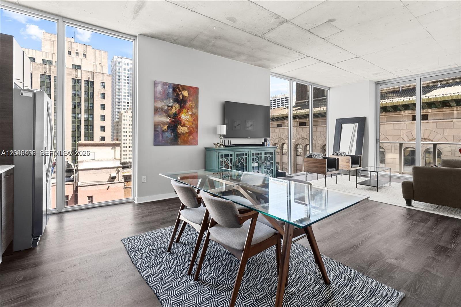 A modern apartment living and dining area features floor-to-ceiling windows and a concrete ceiling — 151 SE 1st St # 1402, Miami FL 33131, MIAMI, FL