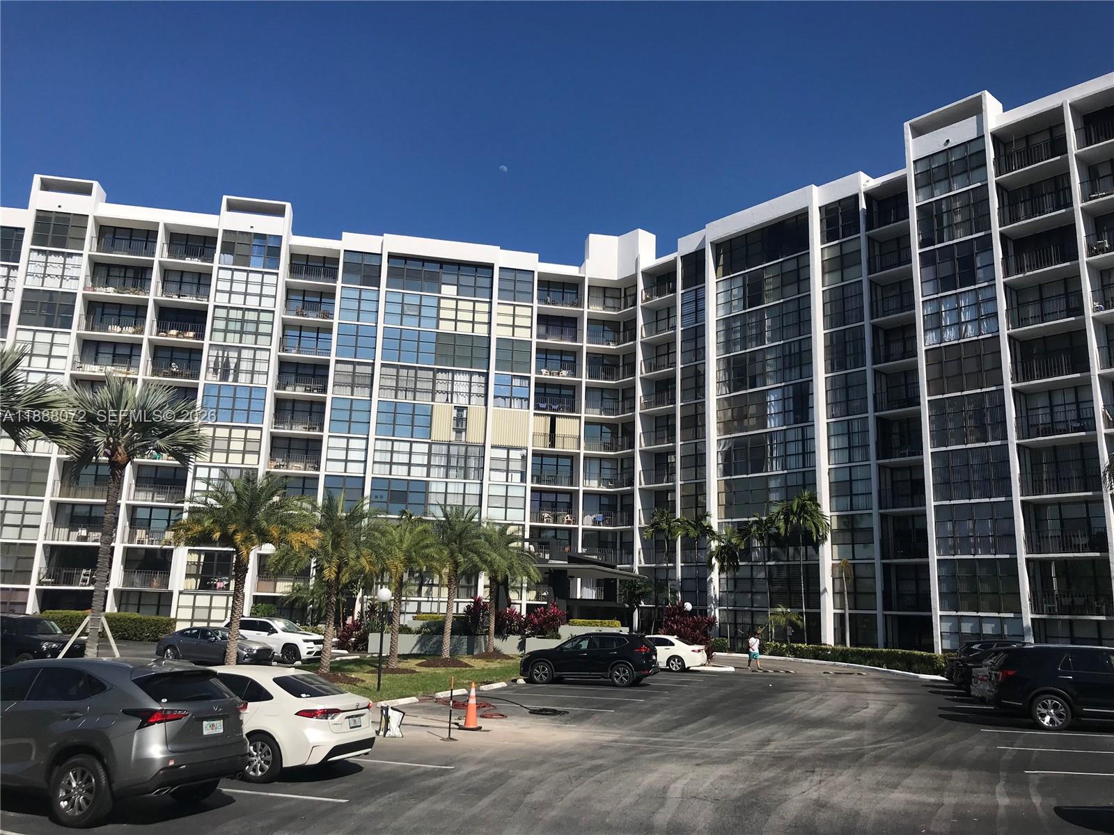 A multi-story residential building with a parking lot in the foreground under a clear sky — 1000 Parkview Dr # 627, Hallandale Beach FL 33009, HALLANDALE BEACH, FL
