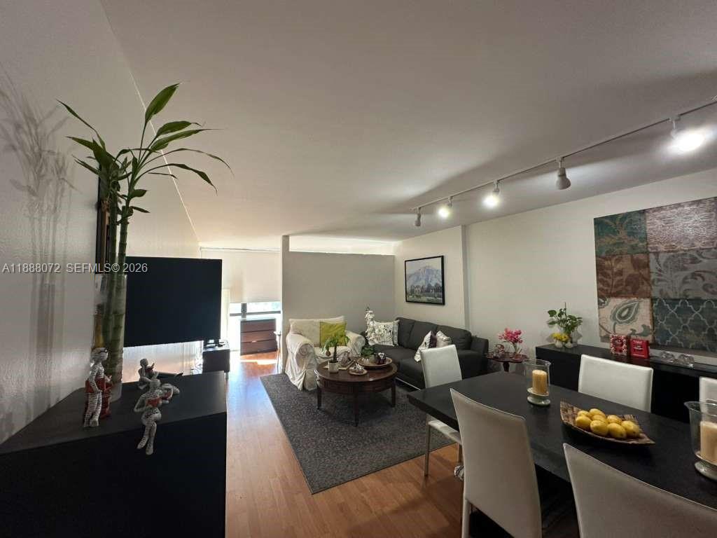 A living and dining room area features hardwood floors, track lighting, and neutral walls — 1000 Parkview Dr # 627, Hallandale Beach FL 33009, HALLANDALE BEACH, FL