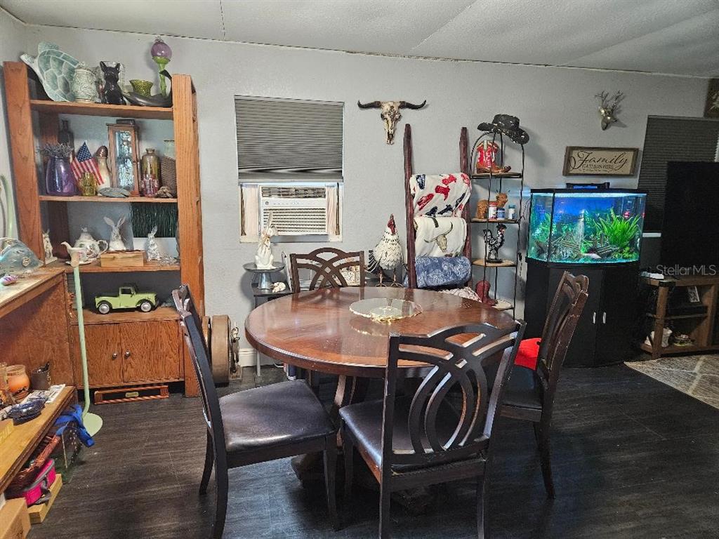 A dining room features a round wooden table, four chairs, a bookshelf, and an aquarium — 425 ORANGE BOULEVARD, POLK CITY, FL