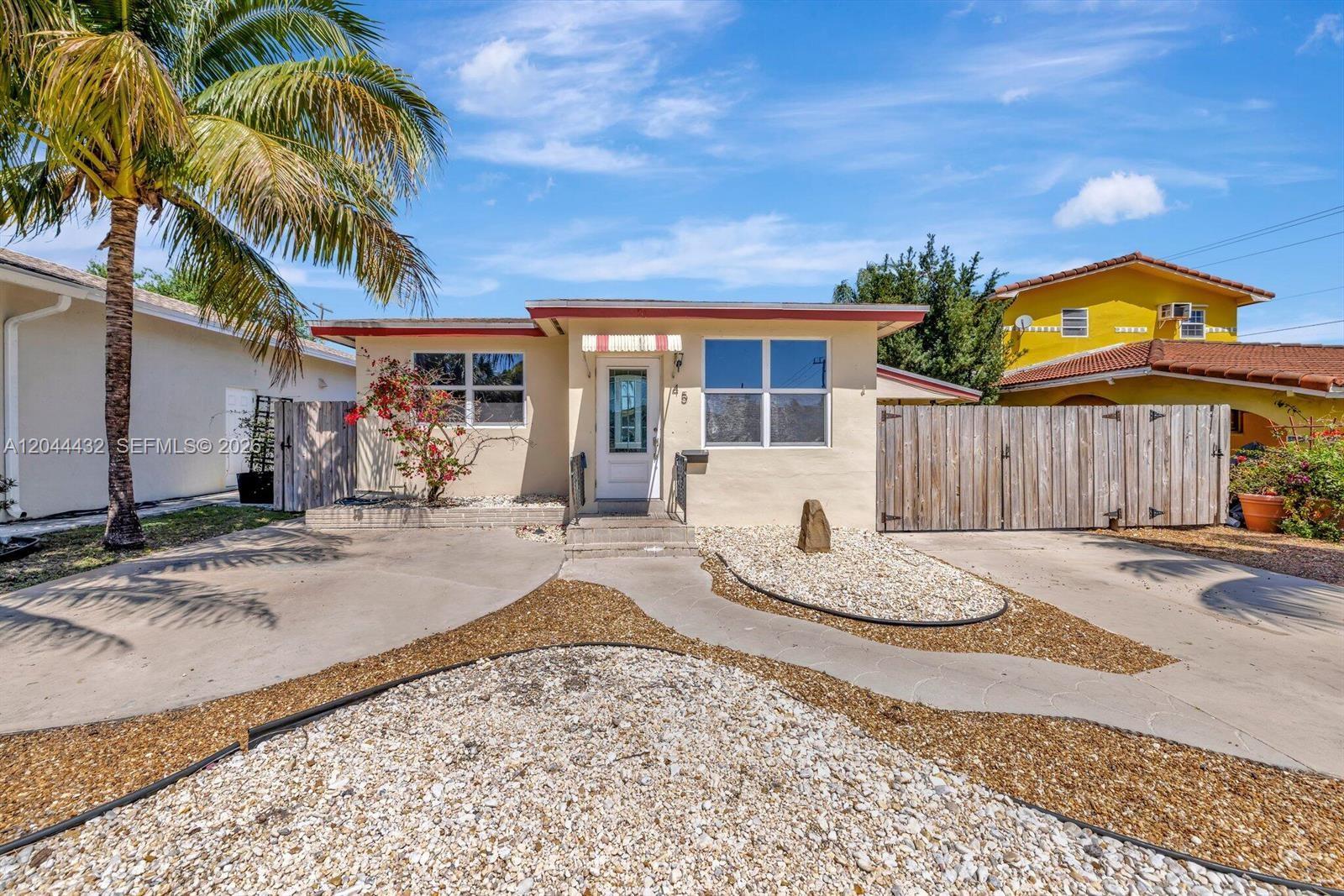 A single-story house with a beige exterior, a palm tree, and a gravel front yard — 45 SE 14th St, Dania Beach FL 33004, DANIA BEACH, FL